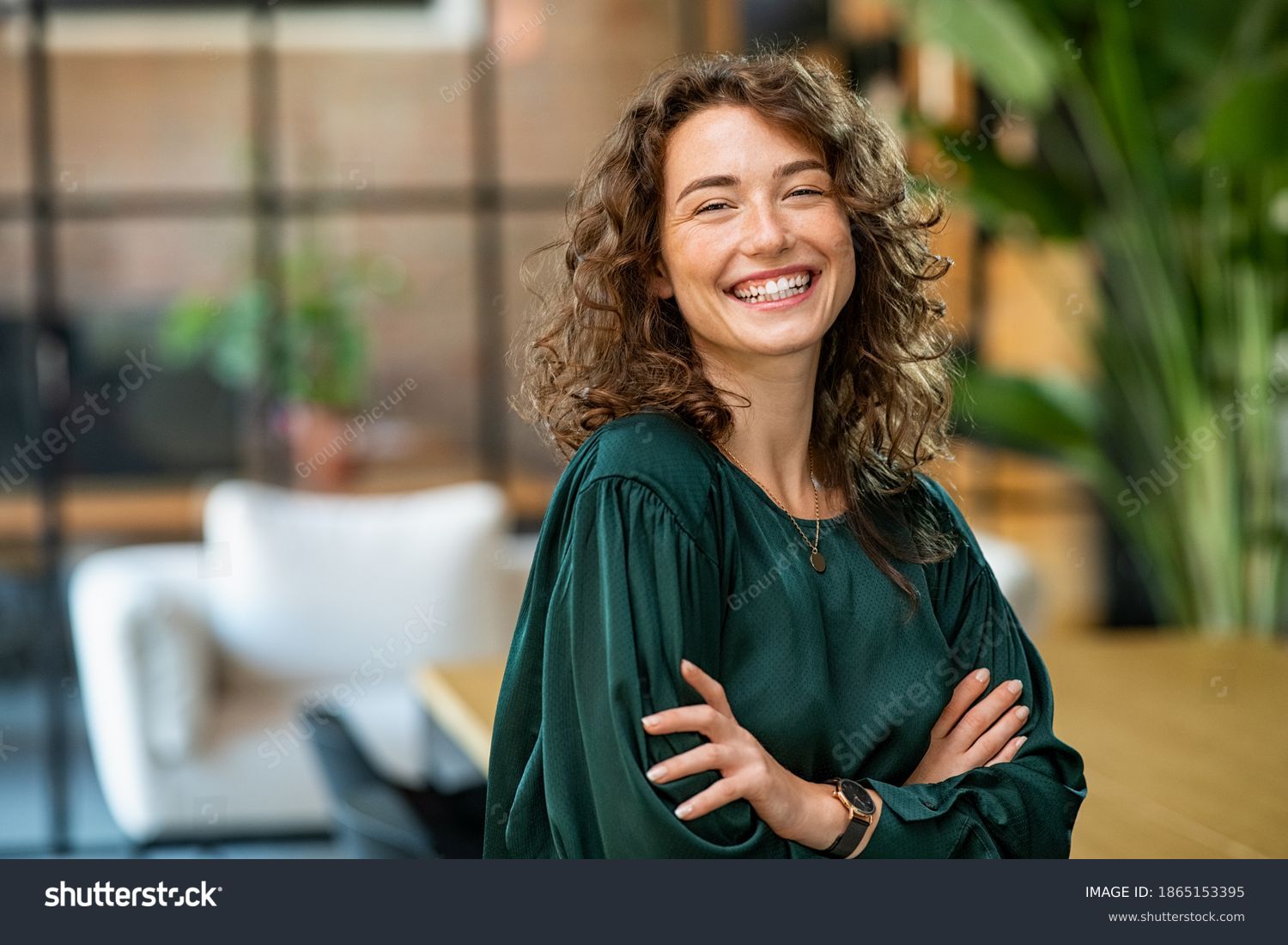 stock-photo-portrait-of-young-smiling-woman-looking-at-camera-with-crossed-arms-happy-girl-standing-in-1865153395